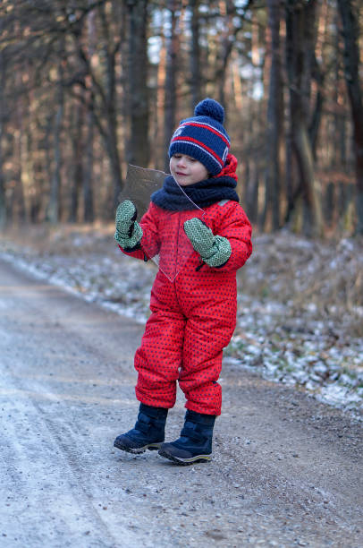 4-5 jahre alter junge bei einem spaziergang im winterwald während coronavirus einschränkungen - child winter snow 4 5 years stock-fotos und bilder