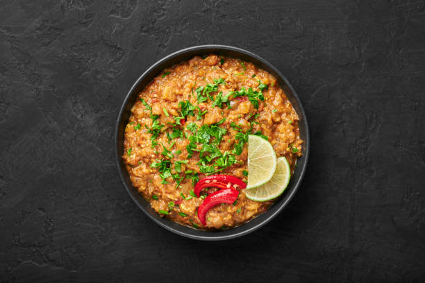 istock Baingan Bharta or Roasted Mashed Eggplant in black bowl on dark slate table top. Bhurta is indian cuisine puree dish of fire roasted eggplant and masala. Top view 1281422087