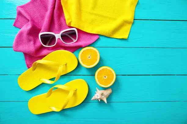 Photo of Summer fun time and accessories on blue wooden background. Mock up. Flip flops, towels, sunglasses, fruits and shell.