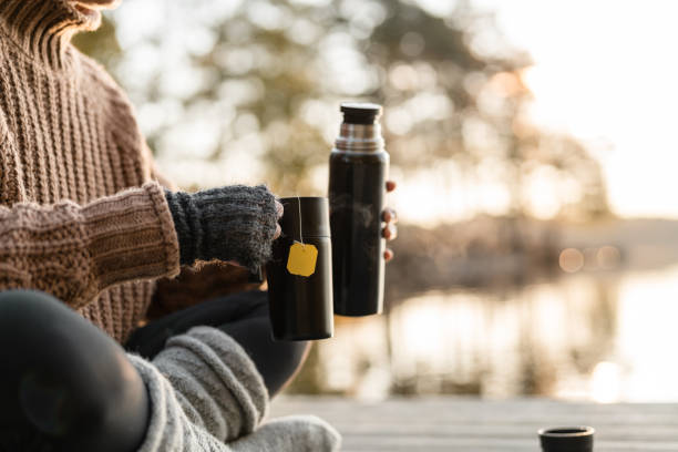 Teddy bear with metal thermos in autumn forest
