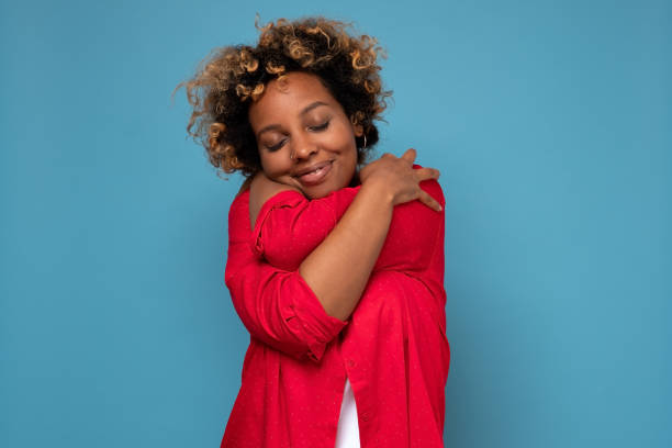 African american woman with curly hair hugging herself stock photo