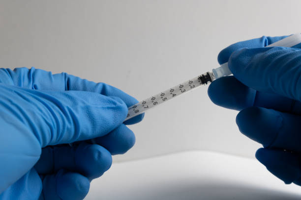 istock hands protected with blue glove uncovering a needle syringe 1281424018