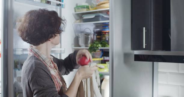 istock Mature woman is placing groceries into refrigerator 1281426904