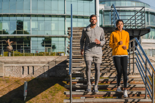 istock Fit young couple going down the stairs while running together against urban background 1281427003