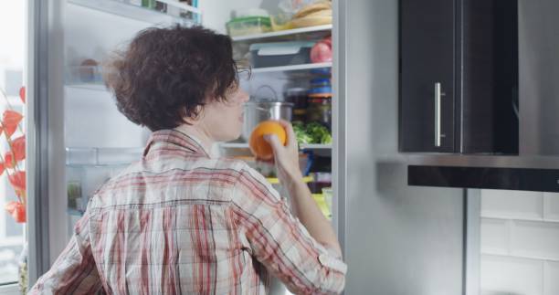 istock Mature woman is taking an orange from the refrigerator 1281427029