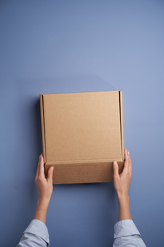 Woman hands open empty cardboard box, top view. Female hands holding gift or present box. Parcel delivery