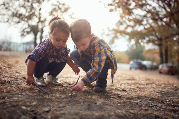 istock Little brother and sister digging the ground with sticks 1281428189