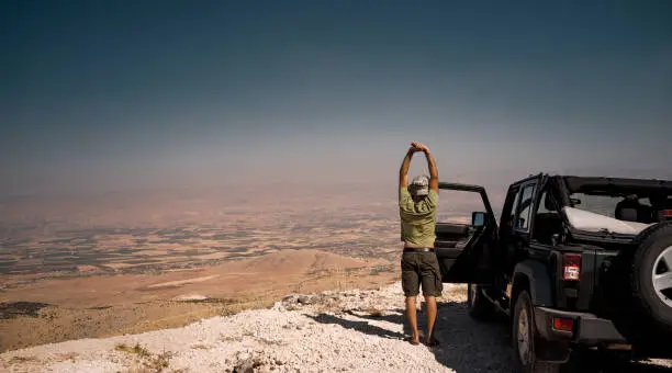 Tourist on the Break from a Long Ride. Standing near the Car and Stretching. Enjoying Amazing View of Bekaa Valley. Active Summer Vacation. Road Trip. Freedom Concept. Lebanon