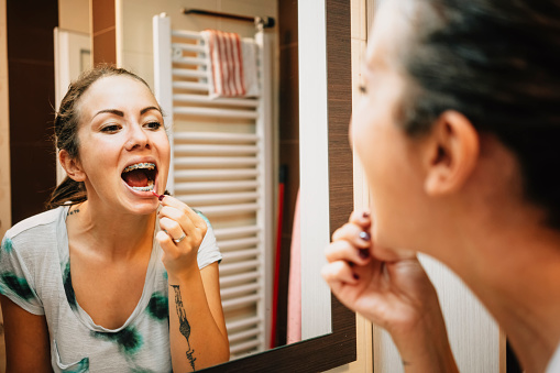 Woman cleaning her teeth's with interdental brush in bathroom