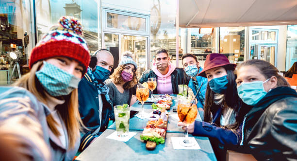 friends taking selfie outside at cocktail bar - new normal lifestyle concept with young people having fun together at restaurant cafe covered by face masks - vivid filter with focus on central guy - apres ski fotos imagens e fotografias de stock