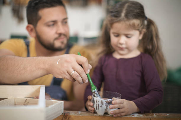 istock Father and daughter painting wooden frame in workshop 1281435168