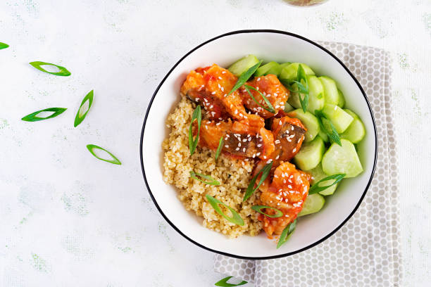 istock Fish fillet cooked in tomato sauce with bulgur and cucumber on a plate on a light background. Healthy eating concept. Easy cooking. Top view, flat lay, copy space 1281435459