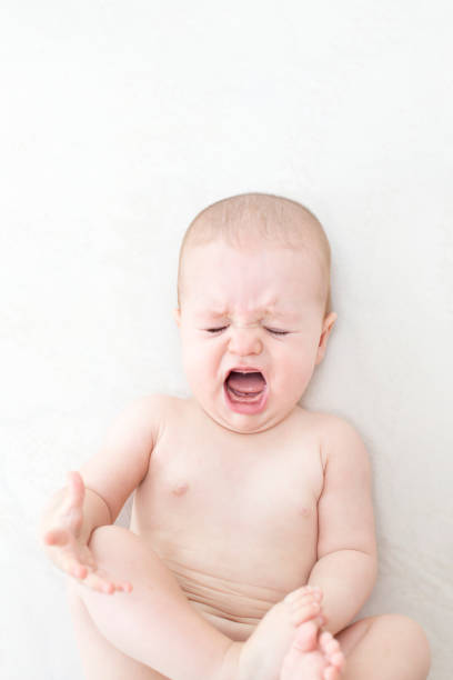 istock Cute baby girl crying on bed 1281435701