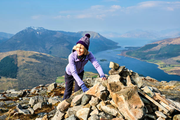 Woman at the summit of the Pap of Glencoe, Scotland Mature adult at the summit of the Pap of Glencoe, Scotland. glencoe scotland photos stock pictures, royalty-free photos & images