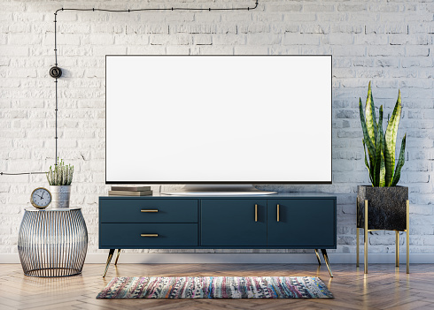 Pantalla en blanco Smart TV en el interior loft con una pared de ladrillo, un elegante armario azul con acentos dorados y una planta de Sansevieria que anima el espacio photo