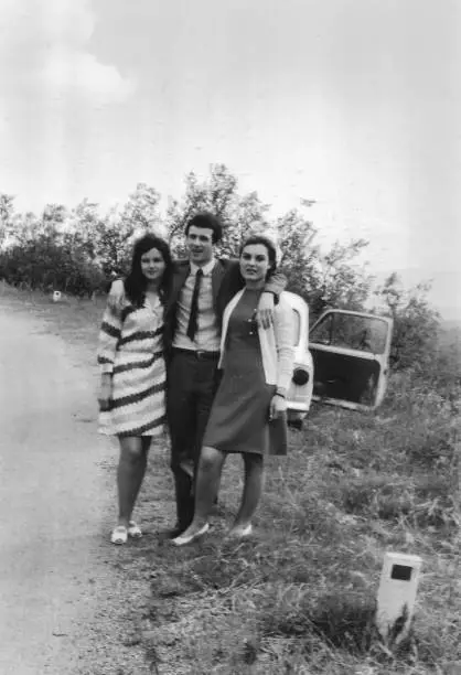 1970s Outdoor portrait of young friends in the countryside. Piandisco Arezzo, Tuscany Italy. Fiat 500. Black and white taken with 35mm film