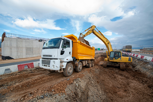 An excavator loading a dumper truck on construction site.