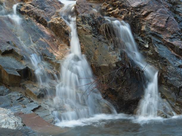 istock Dark stone rocks bathed by a small waterfall. 1281438560