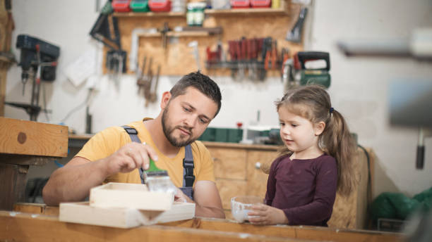 istock Father and daughter painting wooden frame in workshop 1281438740