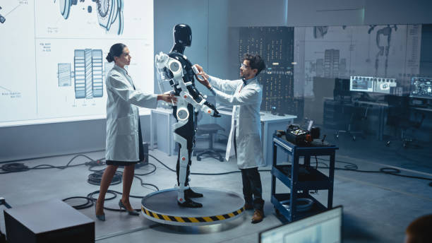 istock In Robotics Development Laboratory: Chief Female Engineer and Top Male Scientist Work on a Bionics Exoskeleton Prototype. Designing Powered Exosuit to Help Disabled People, Hard Labor Workers 1281439911