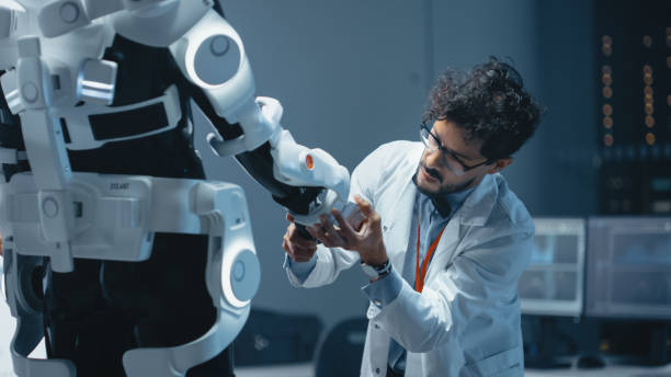 istock In Robotics Development Laboratory: Top Male Scientist Works on a Bionics Exoskeleton Prototype. Team of Engineers Designing Powered Exosuit to Help Disabled People Walk, Labor Workers to Lift Goods 1281439919