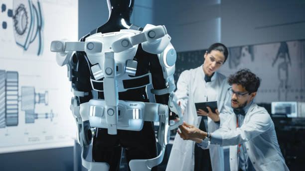 In Robotics Development Laboratory: Chief Female Engineer and Top Male Scientist Work on a Bionics Exoskeleton Prototype. Designing Powered Exosuit to Help Disabled People, Hard Labor Workers In Robotics Development Laboratory: Chief Female Engineer and Top Male Scientist Work on a Bionics Exoskeleton Prototype. Designing Powered Exosuit to Help Disabled People, Hard Labor Workers invalid person stock pictures, royalty-free photos & images
