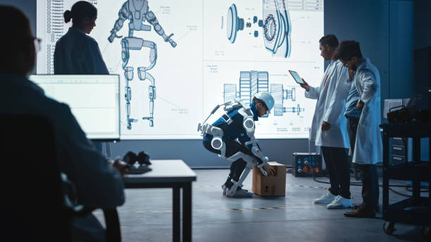 In Development Laboratory: Engineers Look at Robotics Exoskeleton Prototype Presentation with Person Testing it, Lifting Heavy Carboard Box. Designing Wearable Exosuit to Help Warehouse Workers en el laboratorio de desarrollo: los ingenieros miran la presentación del prototipo de exoesqueleto de robótica con la persona que lo prueba, levantando la caja de cartón pesado. diseño de exotraje usable para ayudar a los trabajadores del almacén