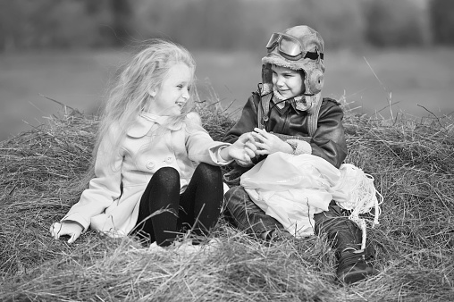 Vintage black and white image from the sixties, a little boy and a little girl posing together smiling at the camera