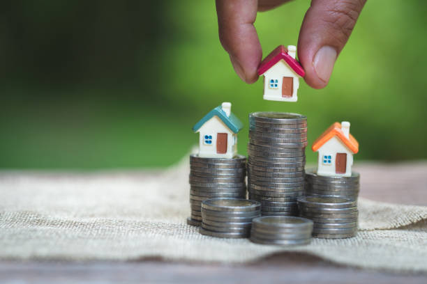 woman's hand putting house model on coins stack. concept for property ladder, planning savings money of coins to buy a home concept property mortgage and investment for a house. - investment real estate construction residential structure imagens e fotografias de stock