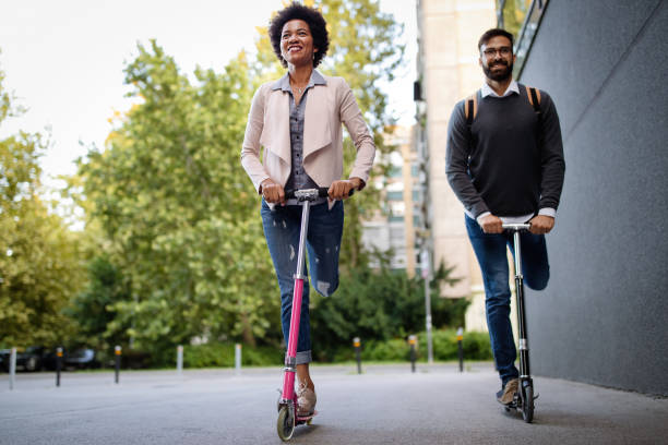 istock Two smiling business people driving electric scooter going to work. 1281445936