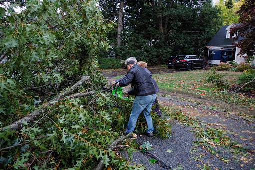 Concord, Massachusetts, USA Oct. 8, 2020 A man and woman clear a road from tree damage after a storm.
