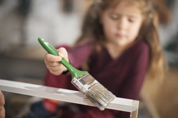 istock Father and daughter painting wooden frame in workshop 1281450208