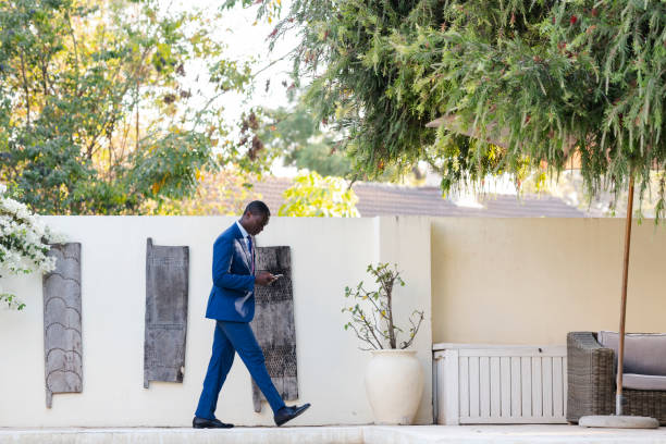 Smart African businessman using phone walking on hotel patio