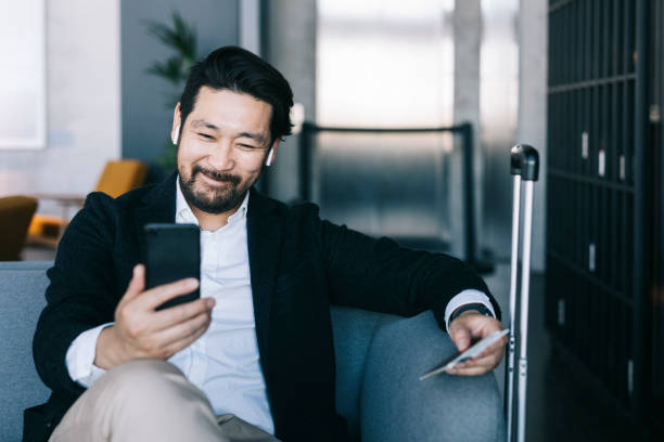 Thanks to technology I can stay connected anywhere in the world. Happy businessman on a video call with his family. airport departure area stock pictures, royalty-free photos & images