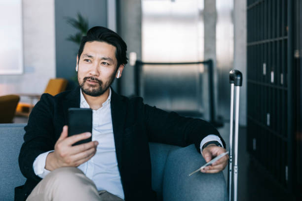 istock Japanese businessman using smartphone at the airport 1281456926
