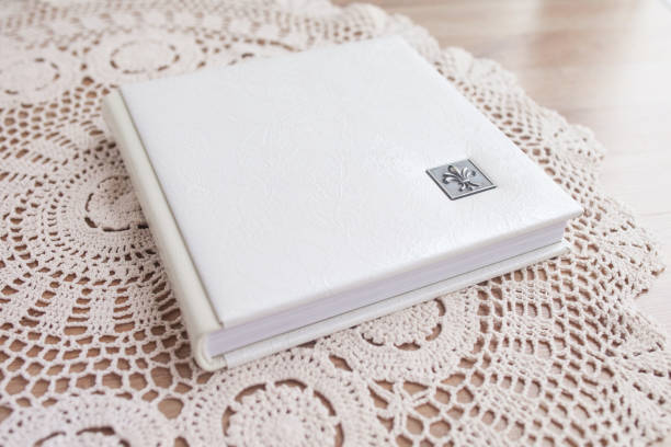 white photo book with leather cover. stylish wedding photo album.  family photoalbum on the table . beautiful notepad or photobook with elegant openwork embossing on a wooden background. - book photo album publication open imagens e fotografias de stock