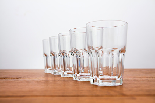 5 glass tumblers in a row in perspective
