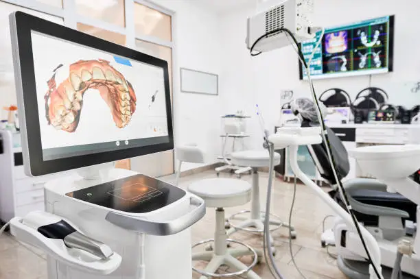 Interior of dental office with modern equipment and dental intraoral scanner with teeth on display, medical system for intraoral scanning. Concept of digital dentistry and dental scanning technology.