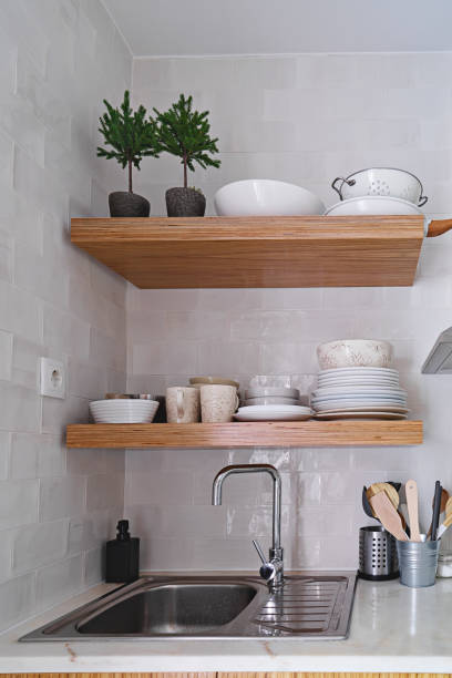 istock Wooden kitchen shelves with tableware on white ceramic tile wall in Scandinavian style 1281463501