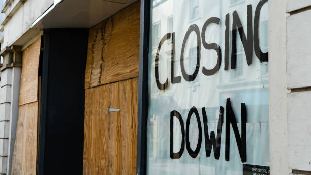 Closing down sign in a boarded-up shop window Closing down sign in a boarded-up shop window closing down sale stock pictures, royalty-free photos & images