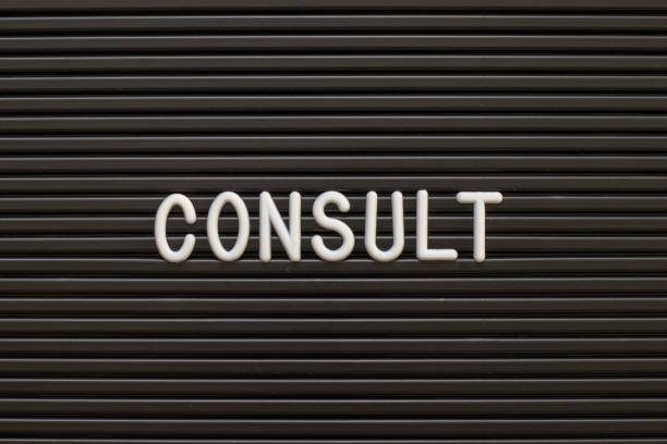 istock Black color felt letter board with white alphabet in word consult background 1281465924