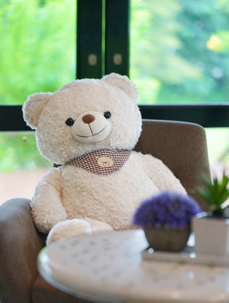 istock Teddy bear. A white fluffy teddy bear is sitting isolately on a sofa by the window. 1281467406