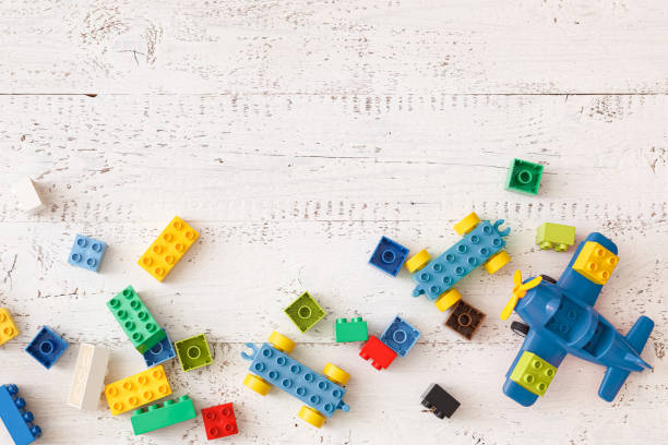 istock Developing multi-colored cubes on a white wooden table. Plastic construction toys. Top view of the blue plane and other educational toys. 1281467476