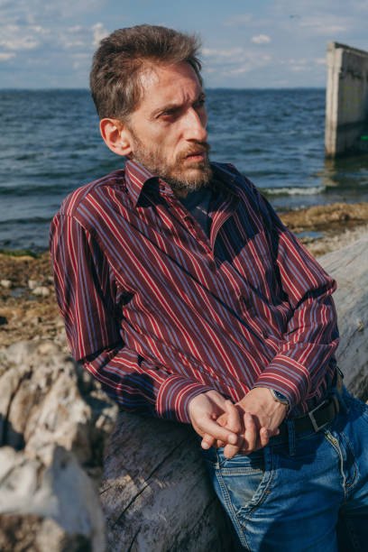 istock Bearded man resting on river bank on old big log 1281468928