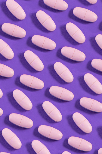 Pink beauty pills on purple background