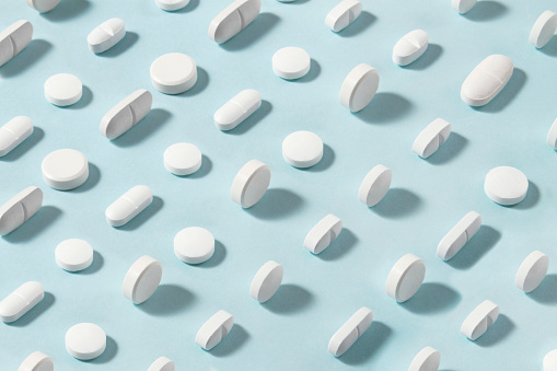 White pills arrangement on soft blue background