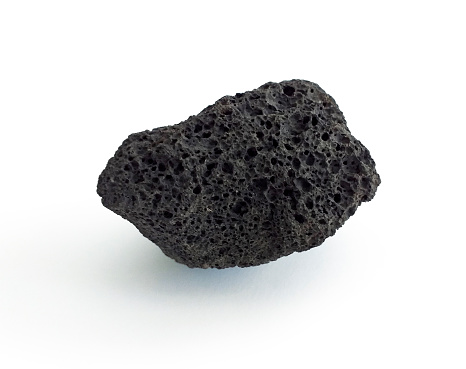 Roca volcánica negra porosa aislada sobre fondo blanco. Piedra de lava, piedra pómez o piedra volcánica con poros distintivos, aislados en blanco. De cerca. photo