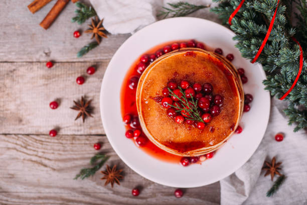 istock Stack of american pancakes with fresh cranberry and jam in white plate on wooden rustic table decorated Christmas tree, delicious dessert for breakfast in winter, vintage style. Copy space. 1281475746