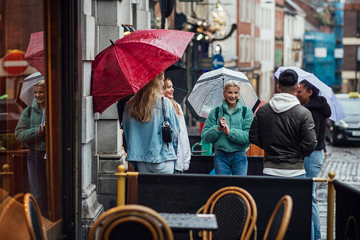 A group of friends meeting up and looking to find somewhere to have food on a rainy day in Newcastle upon Tyne. They are holding umbrellas.