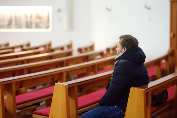 Religious middle age man praying in catholic church. Person closing his eyes, begging for forgiveness and blessing from God. Religious middle age man praying in catholic church. Person closing his eyes, begging for forgiveness and blessing from God. Catholicism is Christianity religion. 11189 stock pictures, royalty-free photos & images